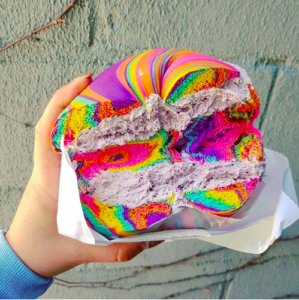 Rainbow swirl bagel with pink strawberry cream cheese, cut in half